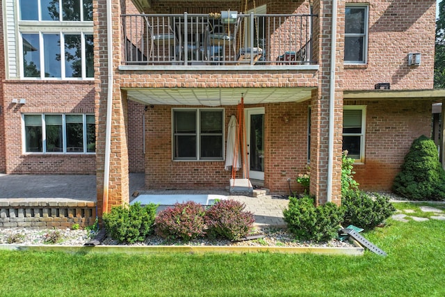 entrance to property with a patio, a balcony, and a lawn