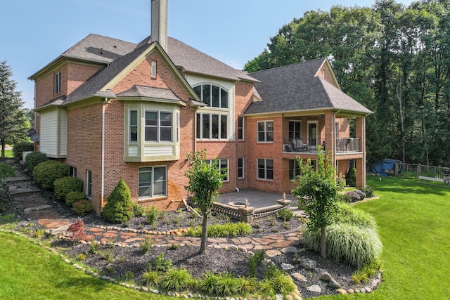 rear view of property featuring a lawn, a patio, and a balcony