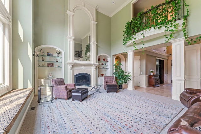 living room with ornate columns, crown molding, a high ceiling, and built in features