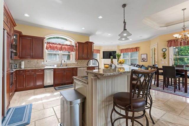 kitchen with hanging light fixtures, an island with sink, decorative backsplash, and a notable chandelier