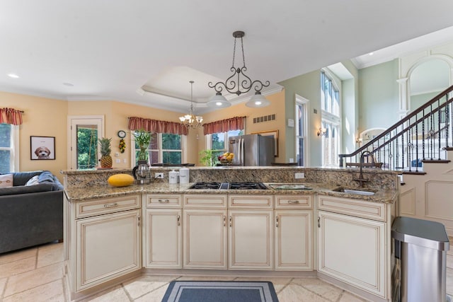 kitchen with stainless steel refrigerator, cream cabinets, light stone counters, and gas stovetop