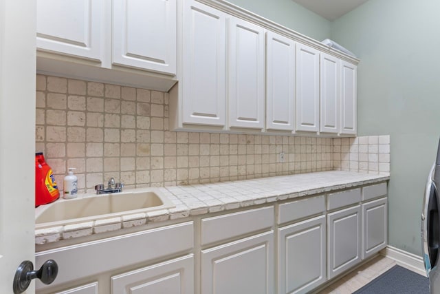 kitchen with tasteful backsplash, sink, and white cabinets