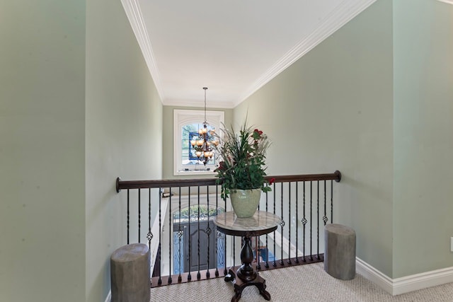 hall with an inviting chandelier, crown molding, and carpet floors