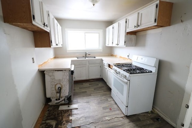 kitchen with white gas range, dark wood-type flooring, sink, and white cabinets