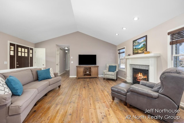 living room featuring lofted ceiling, plenty of natural light, and light wood-type flooring