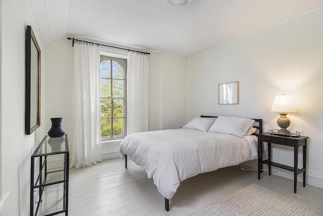 bedroom with lofted ceiling, light hardwood / wood-style floors, and multiple windows