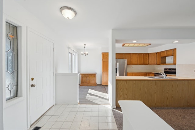 kitchen featuring sink, decorative light fixtures, light tile patterned floors, stainless steel appliances, and decorative backsplash