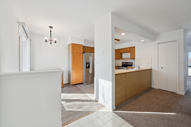 kitchen featuring stainless steel appliances, light carpet, decorative backsplash, and decorative light fixtures