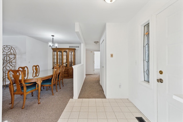 dining space featuring light colored carpet and a notable chandelier