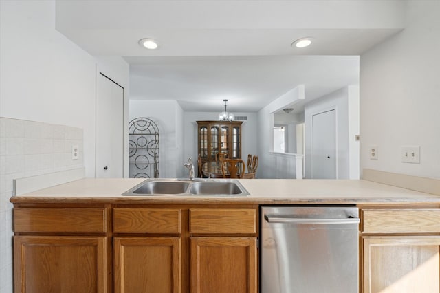 kitchen featuring stainless steel dishwasher, kitchen peninsula, sink, and hanging light fixtures