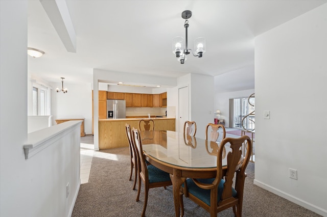 dining area featuring an inviting chandelier and light carpet