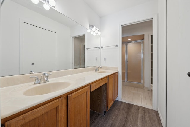 bathroom featuring a shower with door, vanity, hardwood / wood-style floors, and toilet