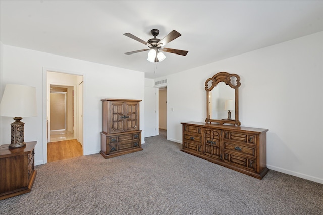 bedroom featuring ceiling fan, light colored carpet, and ensuite bath