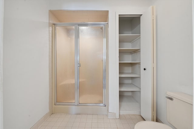 bathroom with a shower with shower door, tile patterned floors, and toilet