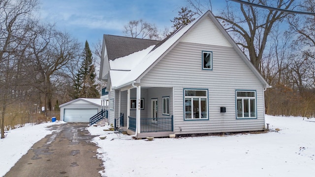 view of snowy exterior with an outbuilding, a porch, and a garage