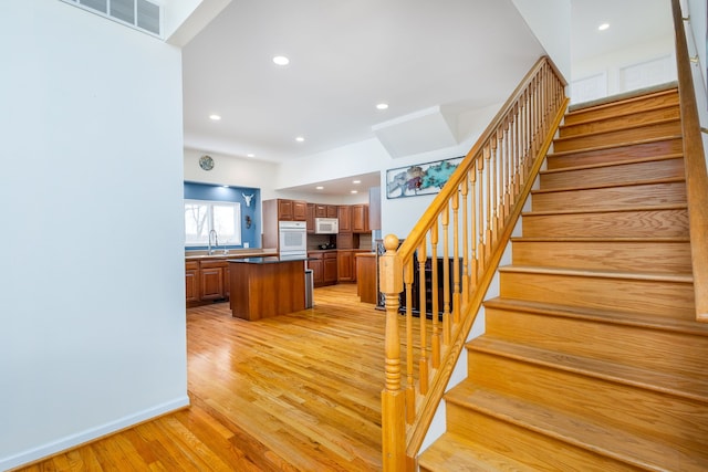 stairway with wood-type flooring and sink