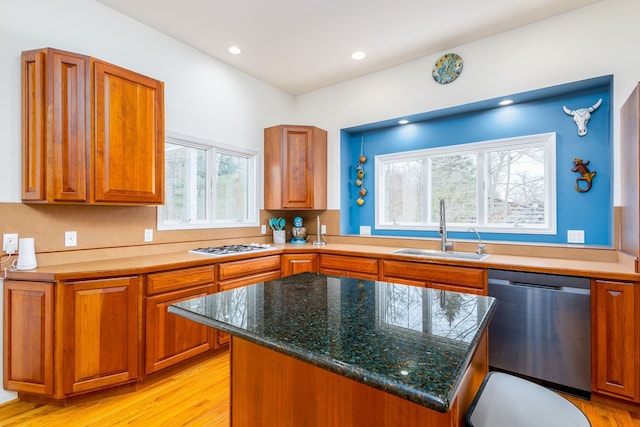 kitchen featuring sink, a center island, dark stone countertops, light wood-type flooring, and stainless steel dishwasher