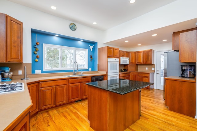 kitchen with a kitchen island, sink, a breakfast bar area, white appliances, and light hardwood / wood-style flooring