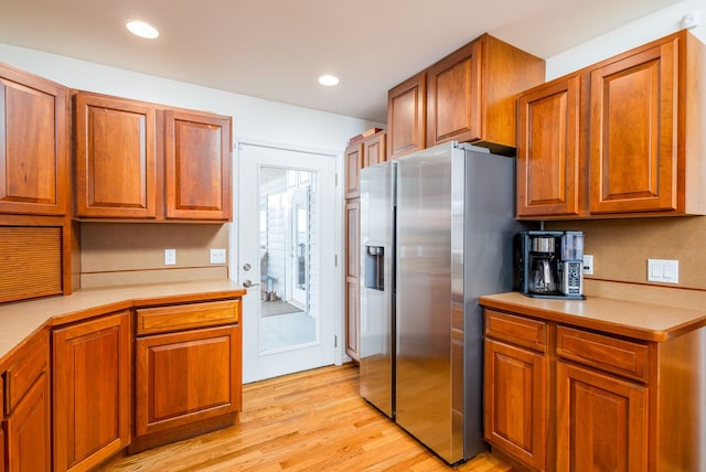 kitchen featuring stainless steel fridge with ice dispenser and light hardwood / wood-style flooring