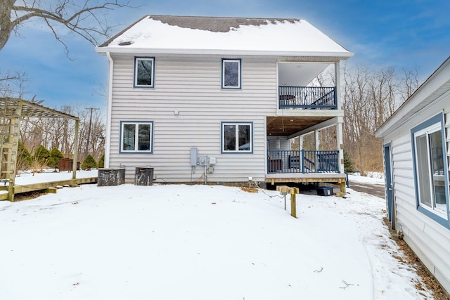 snow covered back of property with a balcony