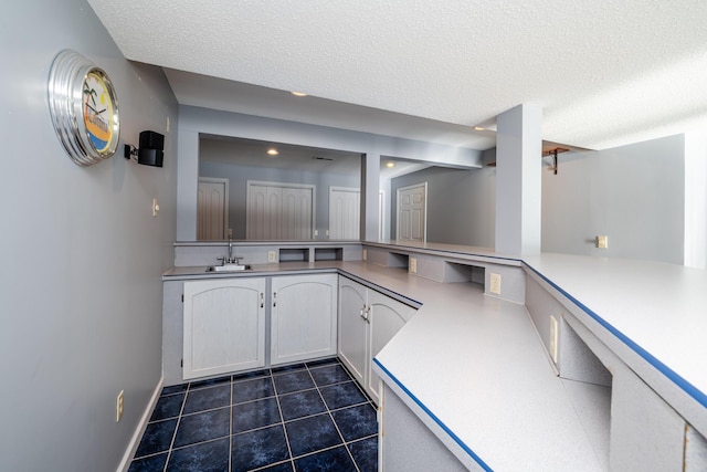 kitchen featuring white cabinets, sink, a textured ceiling, and dark tile patterned floors