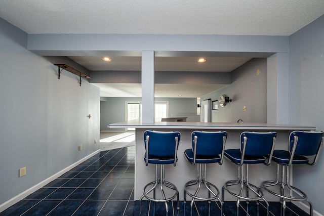 kitchen with a breakfast bar, a textured ceiling, and dark tile patterned floors