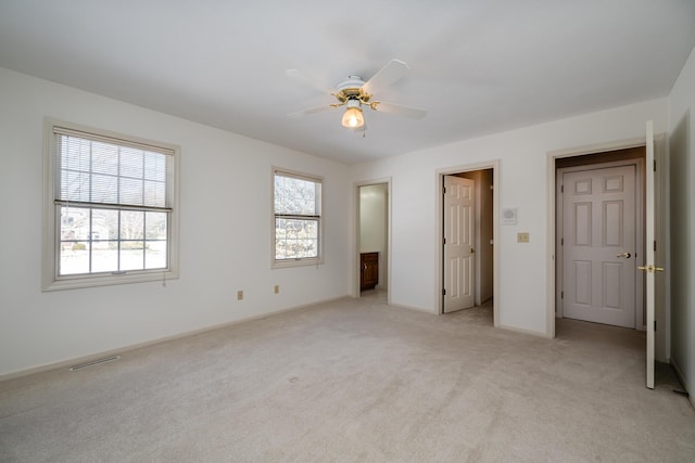 unfurnished bedroom with ceiling fan, light colored carpet, and multiple windows