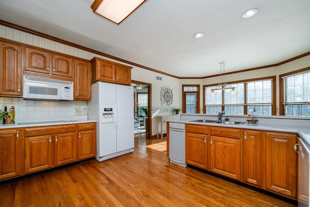 kitchen with sink, crown molding, white appliances, hanging light fixtures, and light wood-type flooring