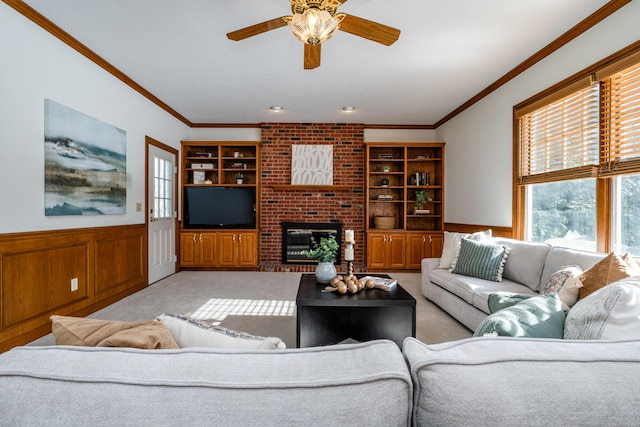 carpeted living room featuring ornamental molding, a brick fireplace, built in features, and ceiling fan