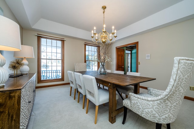 dining room with a chandelier, light colored carpet, and a raised ceiling