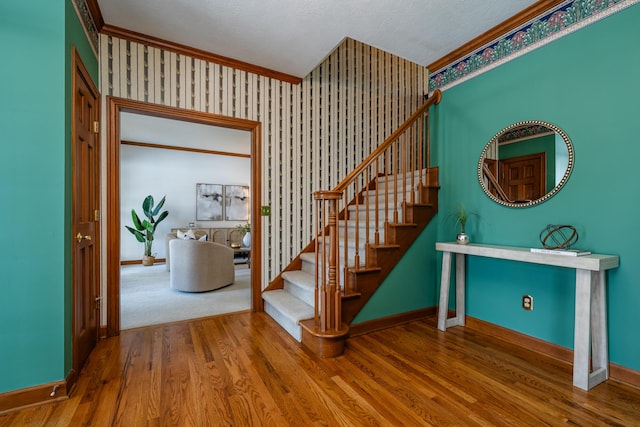 staircase featuring hardwood / wood-style floors and crown molding