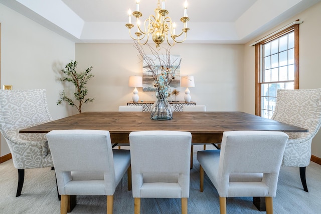 carpeted dining room with a raised ceiling and a chandelier