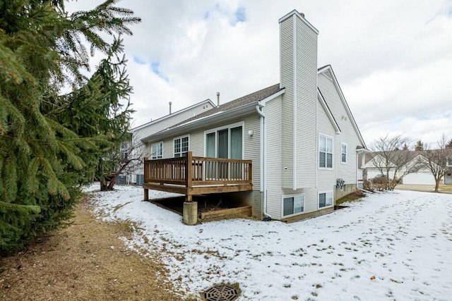 snow covered back of property featuring a wooden deck