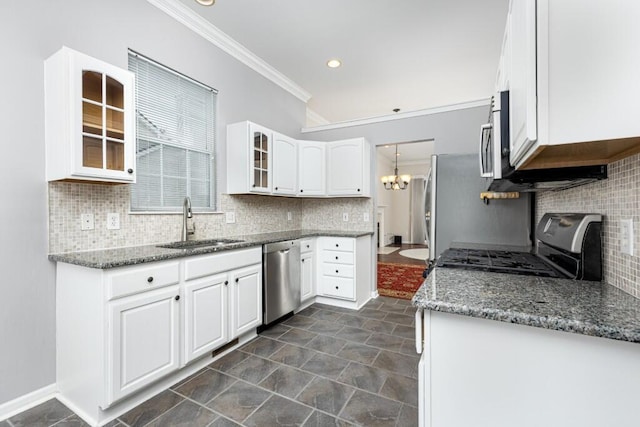 kitchen with appliances with stainless steel finishes, sink, dark stone countertops, white cabinets, and ornamental molding