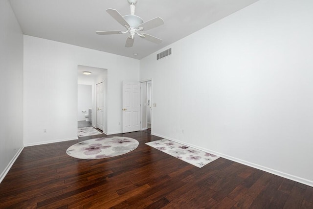 unfurnished bedroom featuring connected bathroom, dark wood-type flooring, and ceiling fan