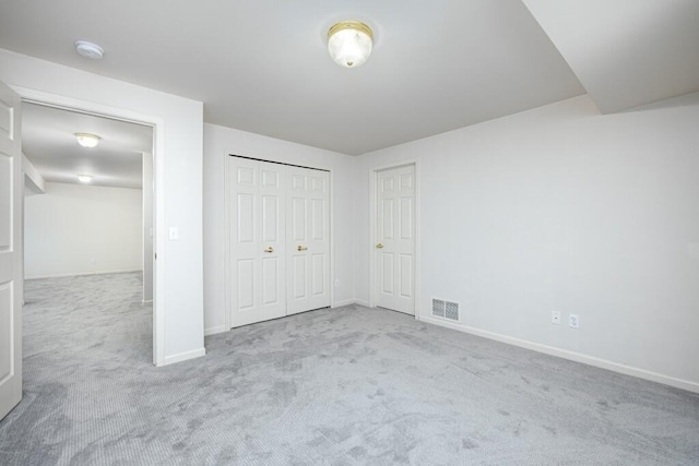 unfurnished bedroom featuring light carpet and a closet