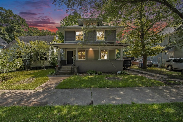 view of front of house featuring covered porch and a lawn