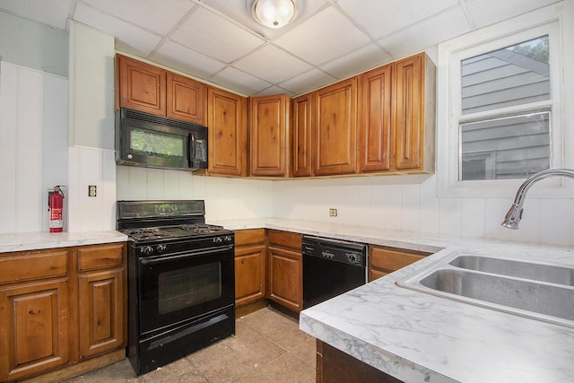 kitchen featuring sink, a paneled ceiling, and black appliances