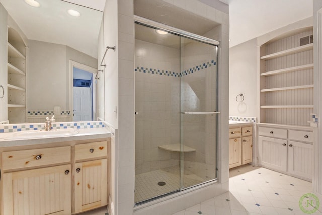 bathroom with vanity, built in shelves, and a shower with shower door