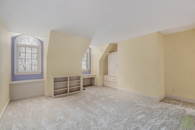 additional living space featuring vaulted ceiling and light colored carpet