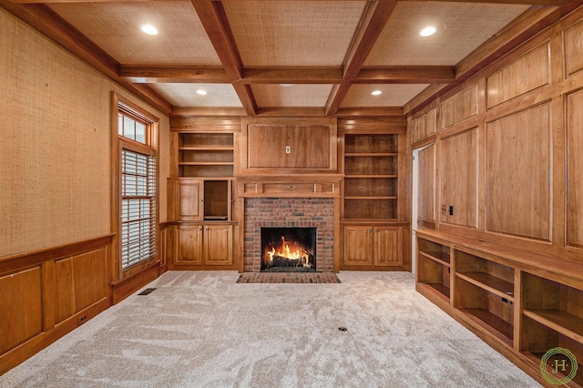 unfurnished living room with built in shelves, a fireplace, coffered ceiling, and beam ceiling