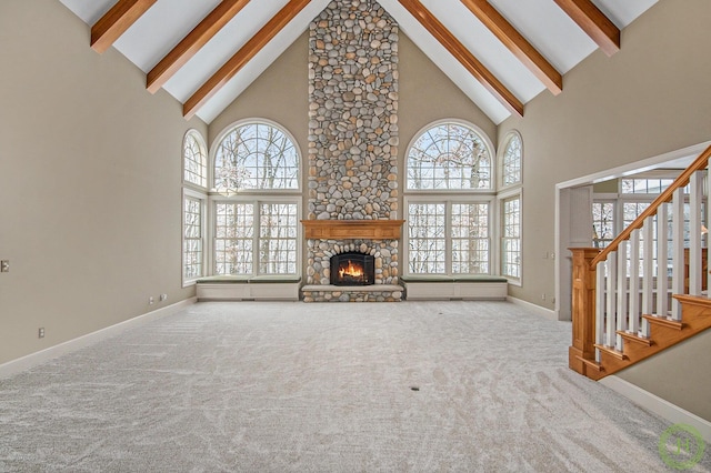 unfurnished living room featuring carpet floors, a fireplace, beamed ceiling, and a high ceiling