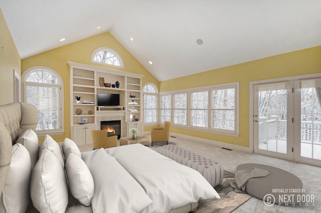 bedroom with light carpet, access to exterior, high vaulted ceiling, and a fireplace