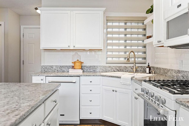 kitchen featuring sink, white appliances, backsplash, light stone countertops, and white cabinets