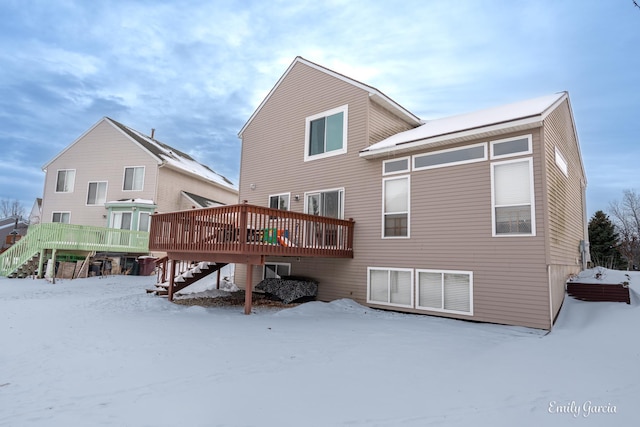 snow covered rear of property with a deck