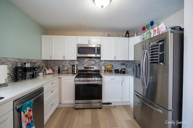 kitchen with tasteful backsplash, white cabinetry, appliances with stainless steel finishes, and light wood-type flooring