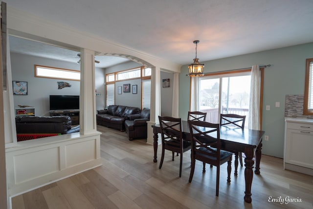 dining area featuring decorative columns, a chandelier, and light wood-type flooring