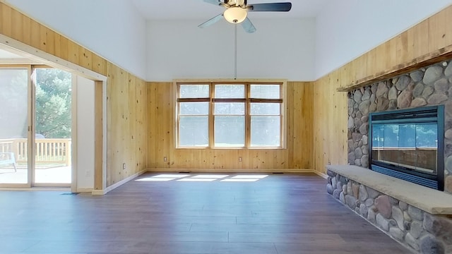 unfurnished living room featuring dark wood-type flooring, a towering ceiling, and wooden walls