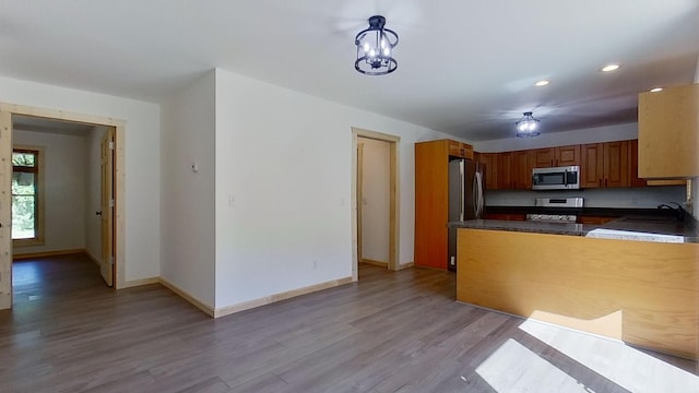 kitchen featuring an inviting chandelier, sink, stainless steel appliances, and light hardwood / wood-style floors