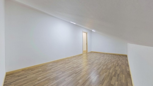 additional living space featuring lofted ceiling and light hardwood / wood-style flooring